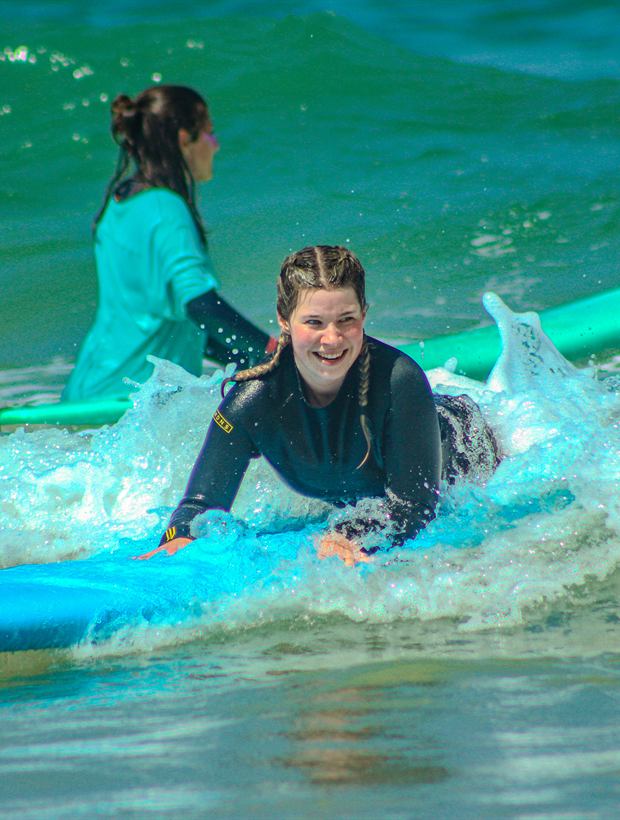 Le coach accompagne une élève sur la vague
