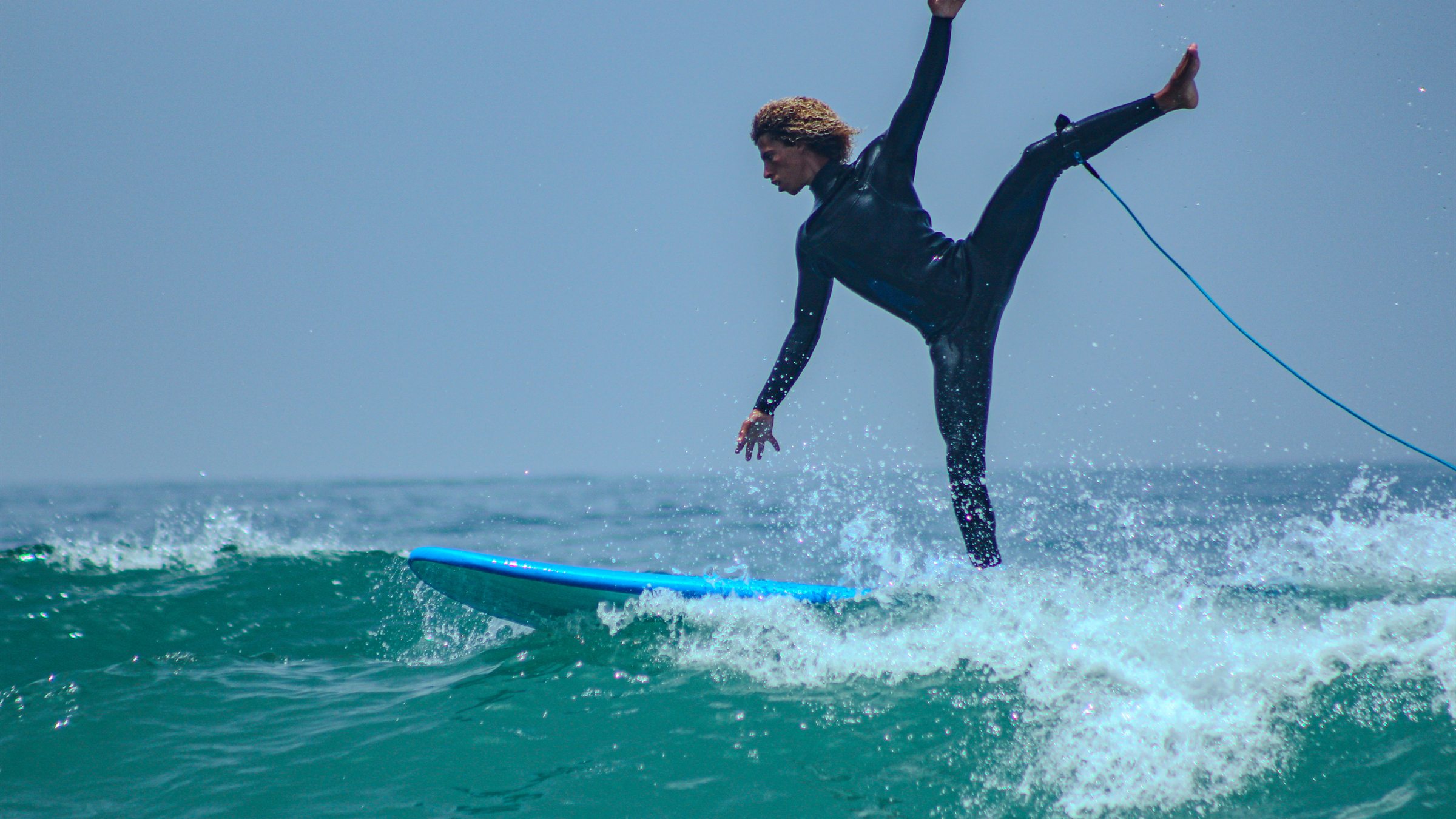 Surfeur engagé dans un virage sur une vague turquoise, au large de Tamraght